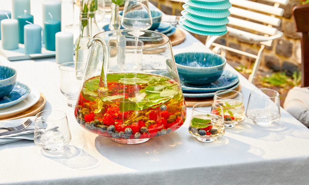 Sommer Bowle mit Früchten auf einem gedeckten Tisch