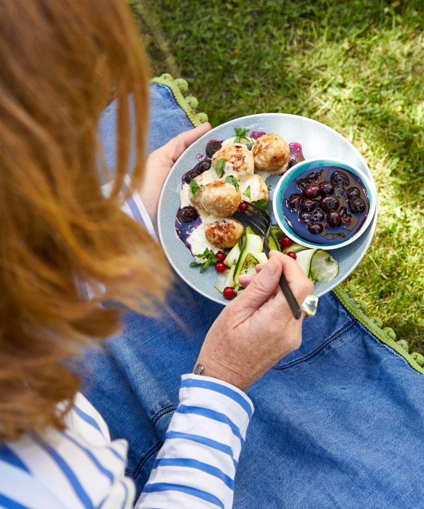 Frau mit Kötbullar und Salat auf einem Teller